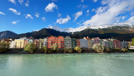 Innsbruck-Austria-colorful-pastel-buildings-capital-Tyrol-Tyrolean-Alps-mountain-backdrop-the-bridge-over-the-Inn-River-Innbrücke-clear-blue-sky-clouds-October-November-autumn-fall-wide-static-shot
