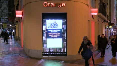 Pedestrians-walk-past-the-French-multinational-telecommunications-corporation-and-phone-operator,-Orange-S