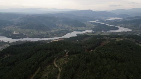 Dirt-road-winds-between-dense-forest-overlooking-wide-winding-river-in-Punxin-Ourense-Galicia-Spain