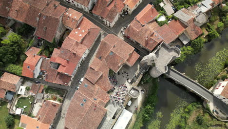 Von-Oben-Nach-Unten-Herauszoomen-–-Luftaufnahme-Einer-Mittelalterlichen-Französischen-Stadt-Mit-Freilufttheater-Und-Grünem-Fluss