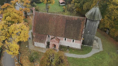 Old,-historic-church-with-a-wooden-tower,-late-autumn,-drone-view
