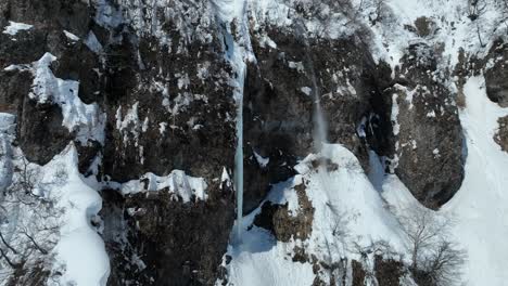 Close-up-inspection-shot-of-snowy-mountain-cliff-face,-snow-powder-falls-off-cliff-edge,-avalanche-starter