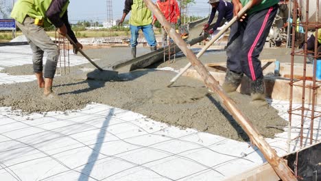 Ziehen-Und-Verteilen-Der-Mischung-Aus-Zement,-Sand-Und-Kies-Zum-Auffüllen-Der-Bodenfläche-Eines-Im-Bau-Befindlichen-Gebäudes-Am-Stadtrand-Von-Bangkok,-Thailand