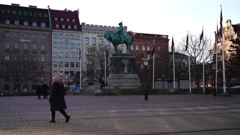 Gente-Caminando-Junto-A-La-Escultura-De-Carlos-X-Gustavo-En-La-Plaza-Principal-De-Malmo,-Suecia