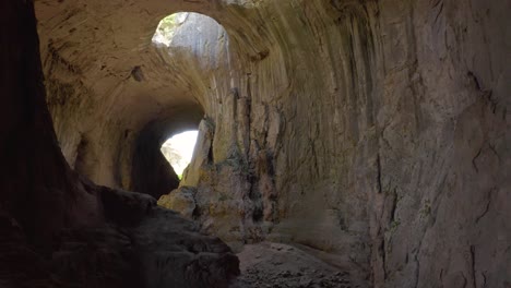 Follow-through-shot-of-the-tunnels-going-to-the-chambers-of-Prohodna-Cave,-passing-by-limestone-walls-and-stalagmites-where-holes-known-as-God's-Eyes-can-be-seen-in-Karlukovo,-in-Bulgaria