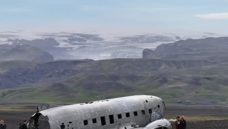 Luftaufnahme-Eines-Verlassenen-Flugzeugs-An-Der-Küste-Islands-Mit-Gletschereiskappen-Auf-Hügeln-Im-Hintergrund,-60 fps