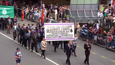 Representatives-from-the-Royal-Australian-Survey-Corps,-Australian-Intelligence-Corps-Association,-Royal-Australian-Signals-Association-walking-down-the-street,-participating-in-Anzac-Day-parade
