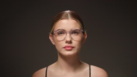 Cute-woman-with-glasses-looking-confused-and-surprised,-black-background