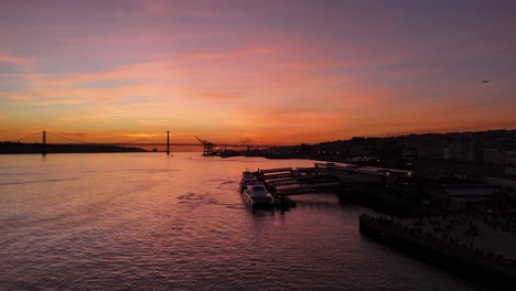 Aerial-parallax-around-ferry-docked-at-regional-port-in-Lisbon-portugal-under-pink-purple-gradient-sunset-sky