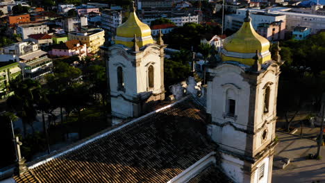 Aerial-view-of-Nosso-Senhor-do-Bonfim-church-back-side,-the-neighbourhood-and-the-ocean-at-background,-Salvador,-Bahia,-Brazil