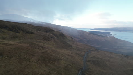 Backward-Circular-Aerial-of-Road-on-Hill-with-Scottish-Lock-in-Background