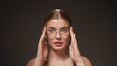 Intelligent-woman-adjusts-her-transparent-glasses,-isolated-black-background