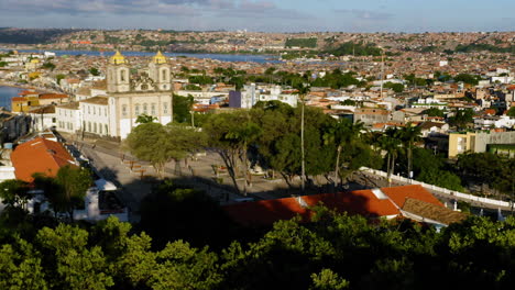 Luftaufnahme-Der-Kirche-Nosso-Senhor-Do-Bonfim,-Der-Umgebenden-Stadt-Und-Dem-Meer-Im-Hintergrund,-Salvador,-Bahia,-Brasilien