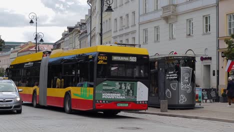 Ein-Bus-Des-öffentlichen-Nahverkehrs-Fährt-Tagsüber-In-Den-Farben-Von-Warschau-Die-Straße-Entlang