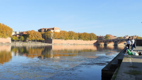 Escena-Tranquila-En-Un-Día-Soleado,-Gente-Descansando-A-Orillas-Del-Río-Garona,-Toulouse