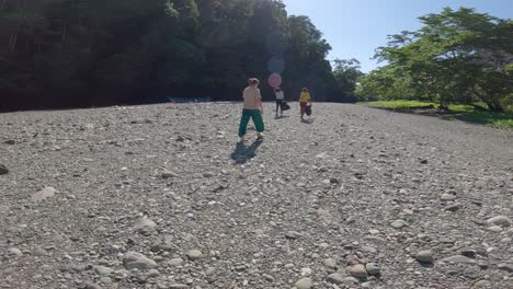 Three-people-walk-along-the-dried-bed-of-the-Blue-River-in-Raja-Ampat,-Indonesia