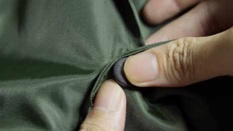 Fingers-Pressing-Attaching-Snap-Button-Of-Green-Jacket,-Close-up