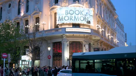 Pedestrians-cross-the-street-in-front-of-the-musical-hit-production,-The-Book-of-Mormon,-is-currently-being-staged-at-the-Calderon-Theater-in-Spain
