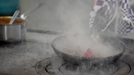 Chef-Cocinando-Carne-De-Res-En-Una-Sartén-Caliente-Que-Se-Prende-Fuego