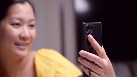 Asian-woman-taking-several-selfies-with-her-modern-cell-phone