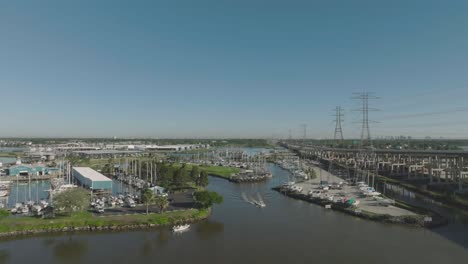 An-aerial-establishing-shot-captures-the-Seabrook-Marina,-with-a-small-power-boat-motoring-into-the-channel-leading-to-Clear-Lake-and-Galveston-Bay-in-Seabrook,-Texas