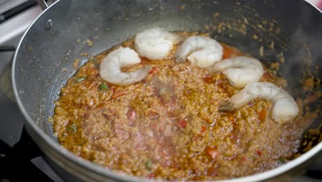 Añadiendo-Delicadamente-Gambas-A-Una-Salsa-Caliente-Y-Burbujeante-En-Un-Plato,-Capturada-En-Cámara-Lenta,-Mostrando-La-Experiencia-Culinaria-Y-El-Placer-De-Cenar.