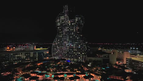 An-aerial-view-of-the-guitar-shaped-Seminole-Hard-Rock-Hotel-and-Casino-illuminated-in-standby-mode-with-sparkling-lights-at-night