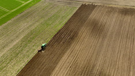 Antena-Arriba-Hacia-Abajo-Del-Tractor-Tirando-De-La-Máquina-De-Arado-En-El-Campo-Agrícola-Al-Sol