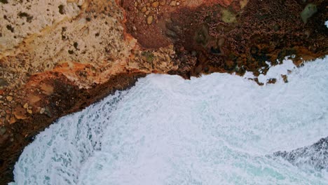 Drone-view-of-strong-whitewater-waves-smashing-red-rocky-cliffs-near-Elliston,-Eyre-Peninsula,-South-Australia