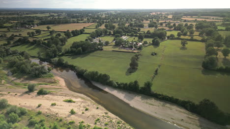 Lateral-Wide-Arc-Aerial-View-of-River-Flowing-Through-Lush-Green-Countryside