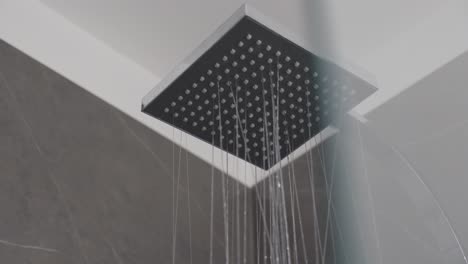 -Nahaufnahme-Von-Wasser,-Das-Aus-Einem-Modernen-Quadratischen-Duschkopf-In-Einem-Zeitgenössischen-Badezimmer-Fließt