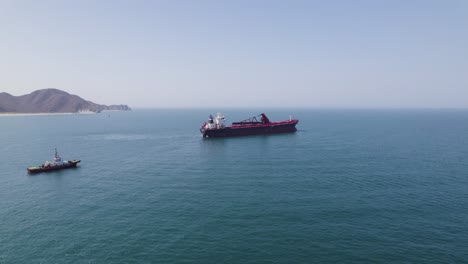 Cargo-ship-departing-from-Santa-Marta-harbor-in-Colombia,-aerial-dolly-forward