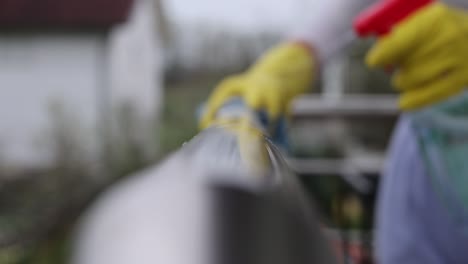 Primer-Plano-De-La-Mano-Femenina-Usando-Un-Paño-Húmedo-Y-Un-Spray-Desinfectante-Para-Manos-Para-Limpiar-La-Barandilla-De-La-Escalera-De-Acero-Inoxidable