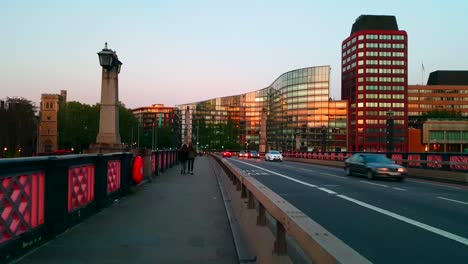 Two-people-walking-across-the-London-Bridge-during-sunset