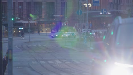 Headlights-flare-as-cars-drive-on-wide-cobbled-street-in-Helsinki-city