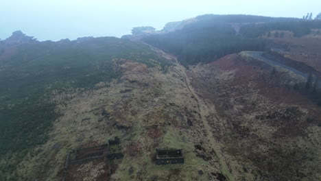 Upward-Back-Reveal-Aerial-of-Tree-Covered-Hill-with-Abandoned-Houses