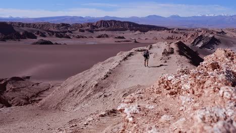 Man-walks-toward-camera:-clean-air-rugged-desert-mountain-viewpoint