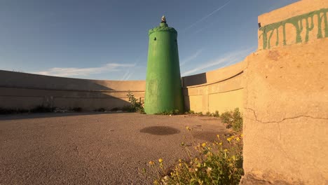A-concrete-facility-with-green-tinted-water-silos,-observed-along-the-shores-of-Spain,-showcasing-the-integration-of-human-made-structures-with-coastal-environments