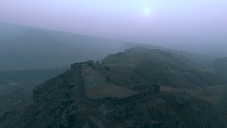 Luftaufnahme-Der-Festungsmauern-Von-Ranikot-Während-Der-Blauen-Stunde-Durch-Neblige-Nebelluft-Im-Distrikt-Jamshoro,-Sindh,-Pakistan