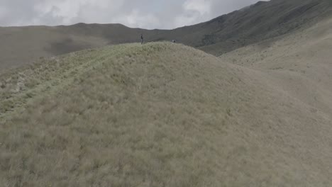 Parallax-drone-shot-of-a-man-standing-on-top-of-a-hill-during-daytime