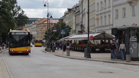 A-colorful-red-yellow-bus-passes-through-a-Warsaw-street-with-tourists-and-residents