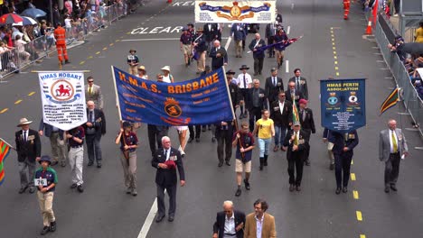 Representatives-from-the-Her-Majesty's-Australian-Ship-Association-walking-down-the-street-of-Brisbane-city,-participating-in-the-annual-Anzac-Day-parade-tradition