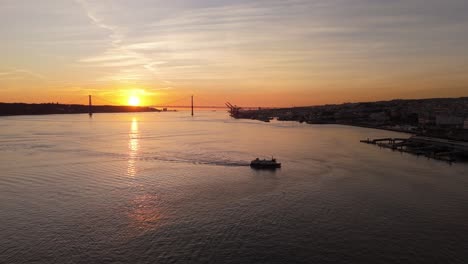 Panoramic-tracking-aerial-follows-tugboat-ferry-crossing-Tagus-river-at-susnet