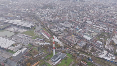 Slow-aerial-footage-flying-away-from-the-smokestack-of-a-power-station-next-to-the-river-in-Belgrade,-Serbia