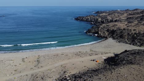 Moto-tourist-with-orange-tent-is-alone-on-quiet-crescent-ocean-beach