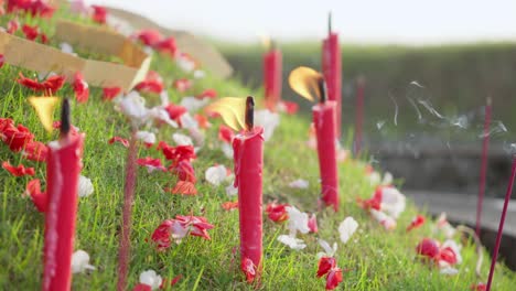 Rote-Kerzen-Brennen-Auf-Einem-Grasbewachsenen-Grab-Mit-Dekorativen-Bunten-Blumen,-Chinesischer-Qingming-Grabfegetag