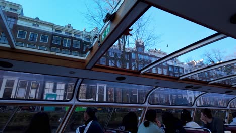 River-Boat-Cruise-Along-Amsterdam-Canals-In-The-Evening,-Looking-Through-Boat-Windows