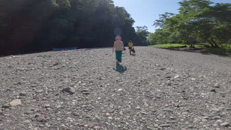 Two-people-walk-along-the-dried-bed-of-the-Blue-River-in-Raja-Ampat,-Indonesia