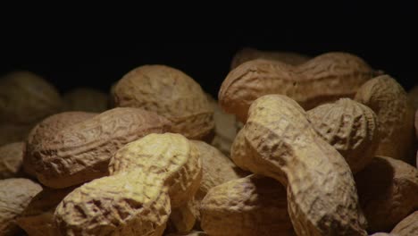 Footage-of-peanuts-rotating-against-a-dark-backdrop,-showcasing-a-close-up-view-of-the-nuts