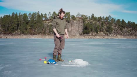 Hombre-Preparando-Un-Agujero-En-El-Hielo-En-Un-Lago-Congelado-Para-Pescar-En-El-Hielo-En-Indre-Fosen,-Noruega